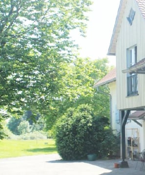 Un edificio a due piani con garage, immerso nel verde e sotto un cielo sereno.