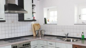 Eine Küche mit weiß gefliesten Wänden, einer Edelstahl-Spüle und einem Fenster darüber.