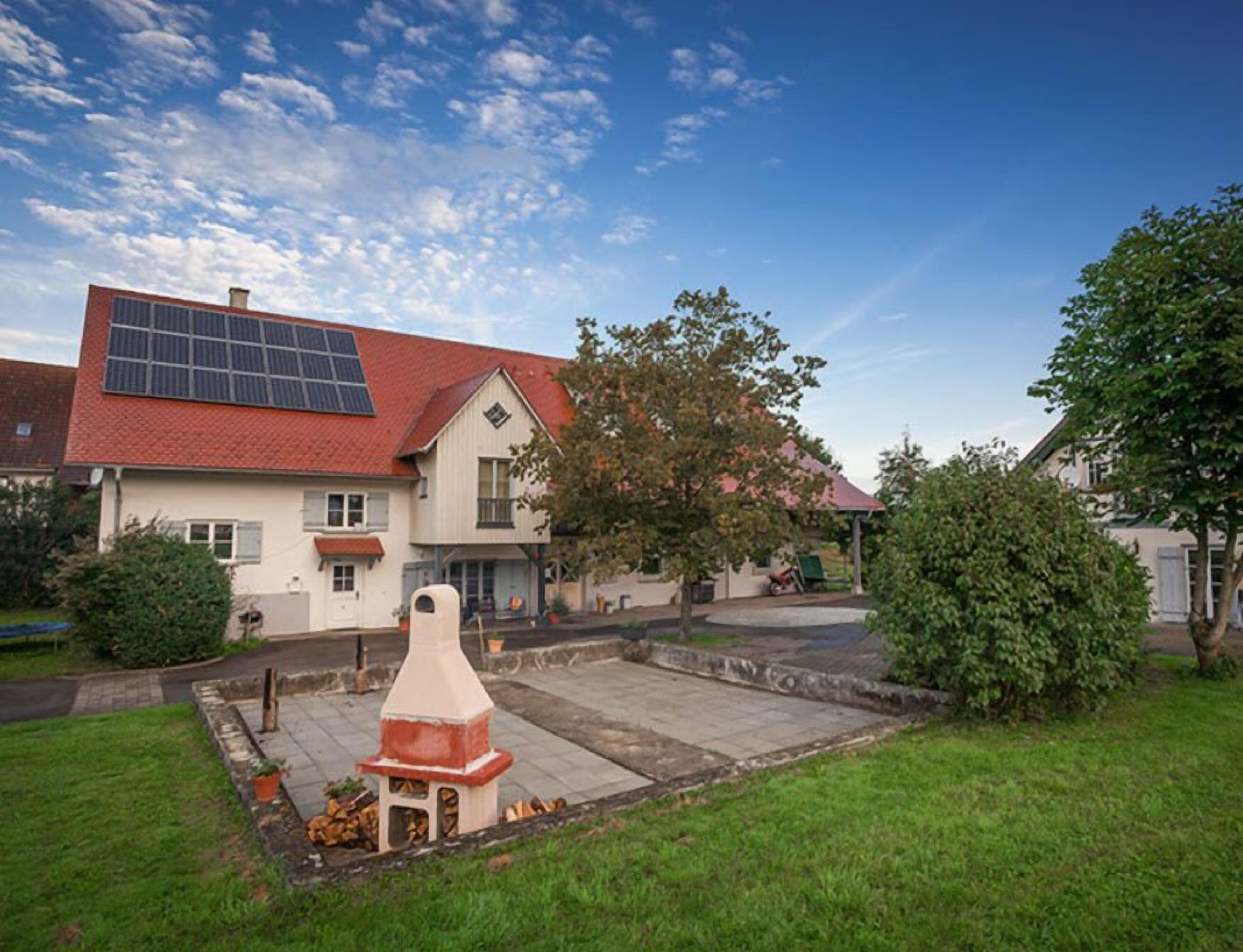 A house with a red roof, a solar panel, and a chimney.