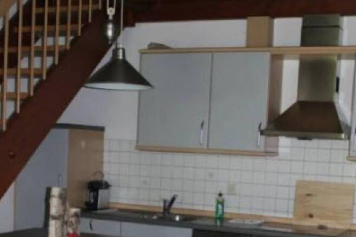 A kitchen with a central island, a stove, and a sink. There are two stools at the island.