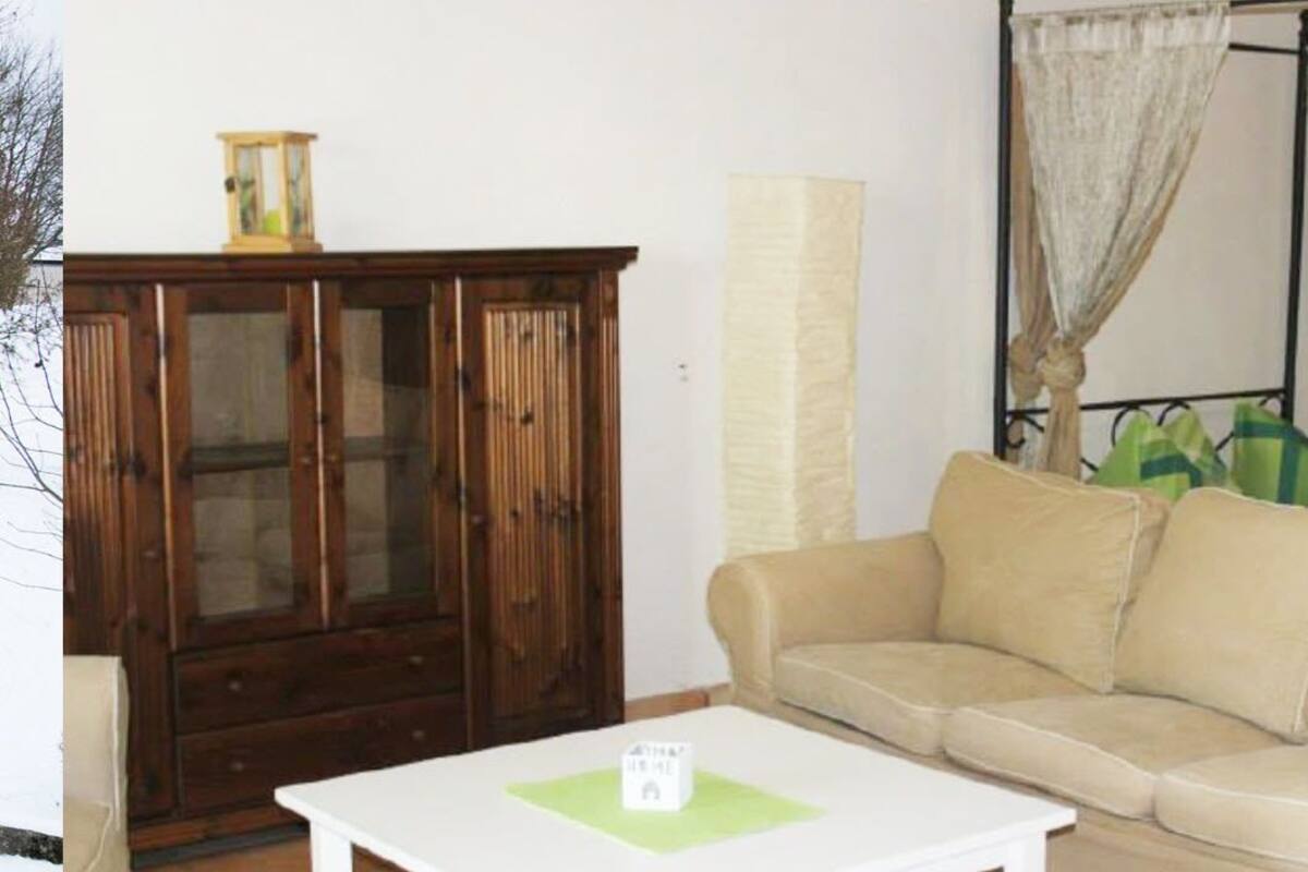 A living room with a beige sofa, a wooden cabinet, and a white coffee table.