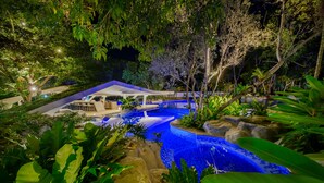 A nighttime view of a swimming pool surrounded by lush greenery and a covered seating area. - Tambuli Seaside Resort and Spa (Lapu-Lapu)