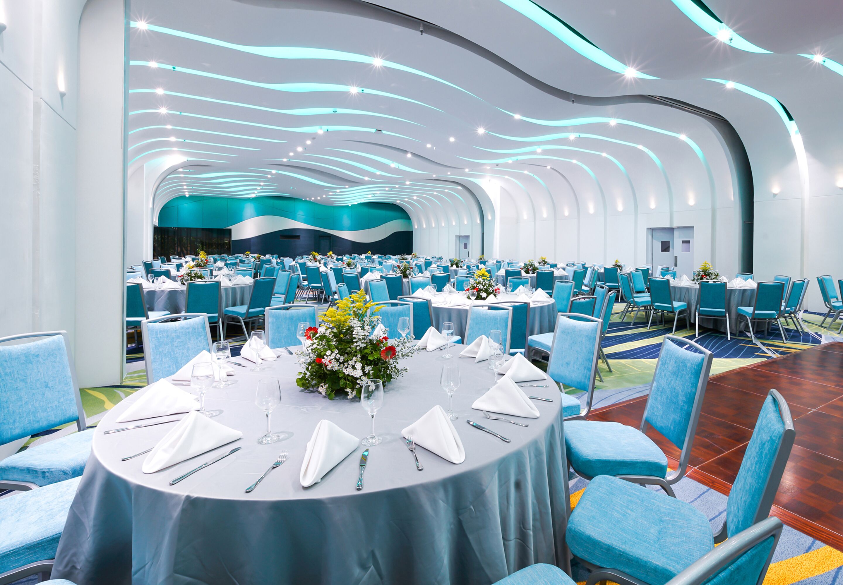 A conference room with round tables, blue chairs, and a modern ceiling design.