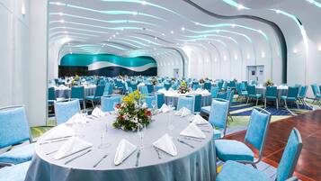 A conference room with round tables, blue chairs, and a modern ceiling design.