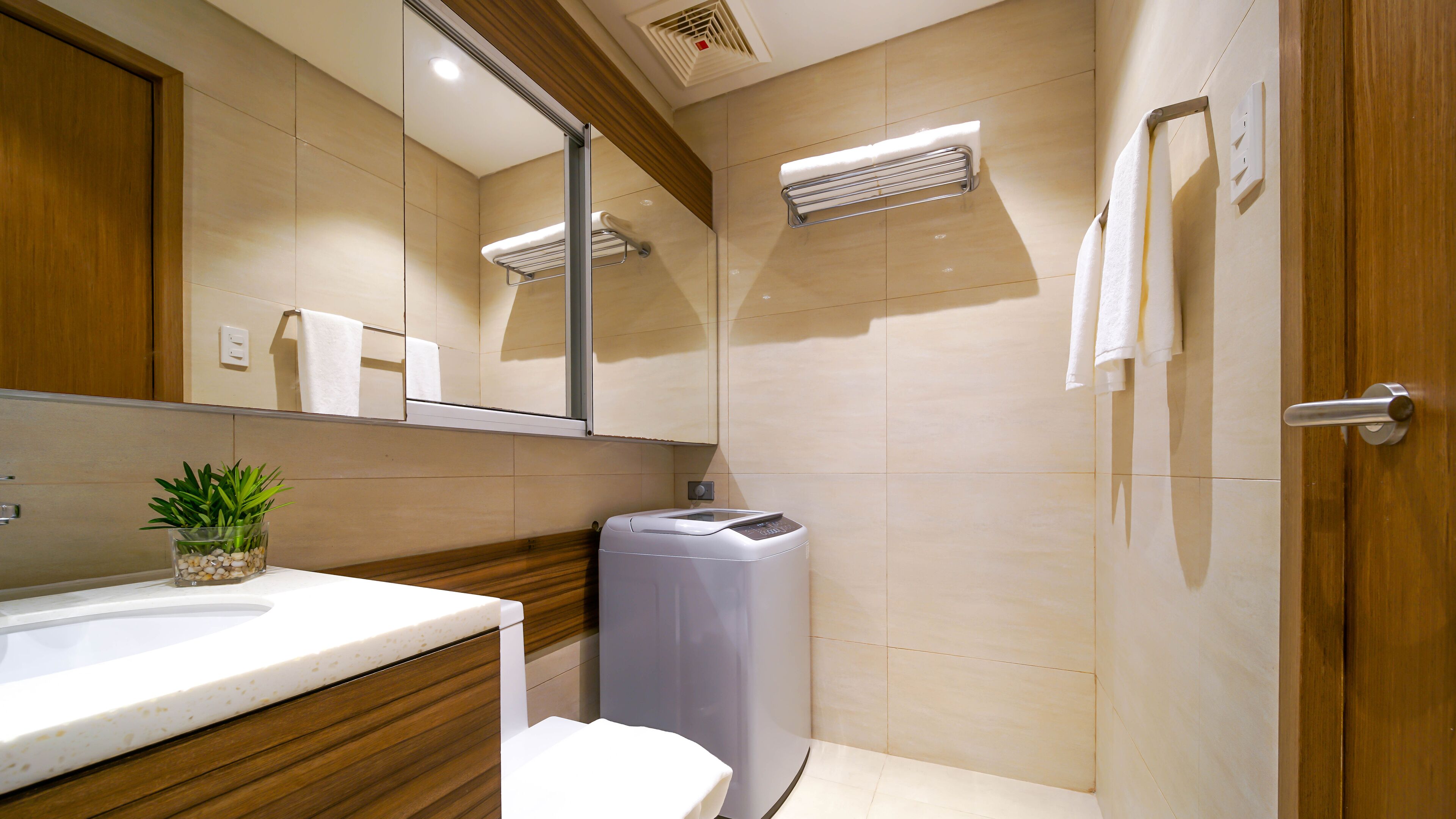 Un baño moderno con tocador de madera, inodoro, un cubo de basura y un perchero para toallas.