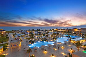A resort with multiple swimming pools, palm trees, and well-lit lounge areas. - Pickalbatros White Beach Taghazout - Adults Friendly 16 Years Plus - Ultra All Inclusive (Taghazout)