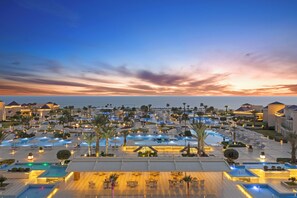 Un resort con varias piscinas, palmeras y vistas a la playa.