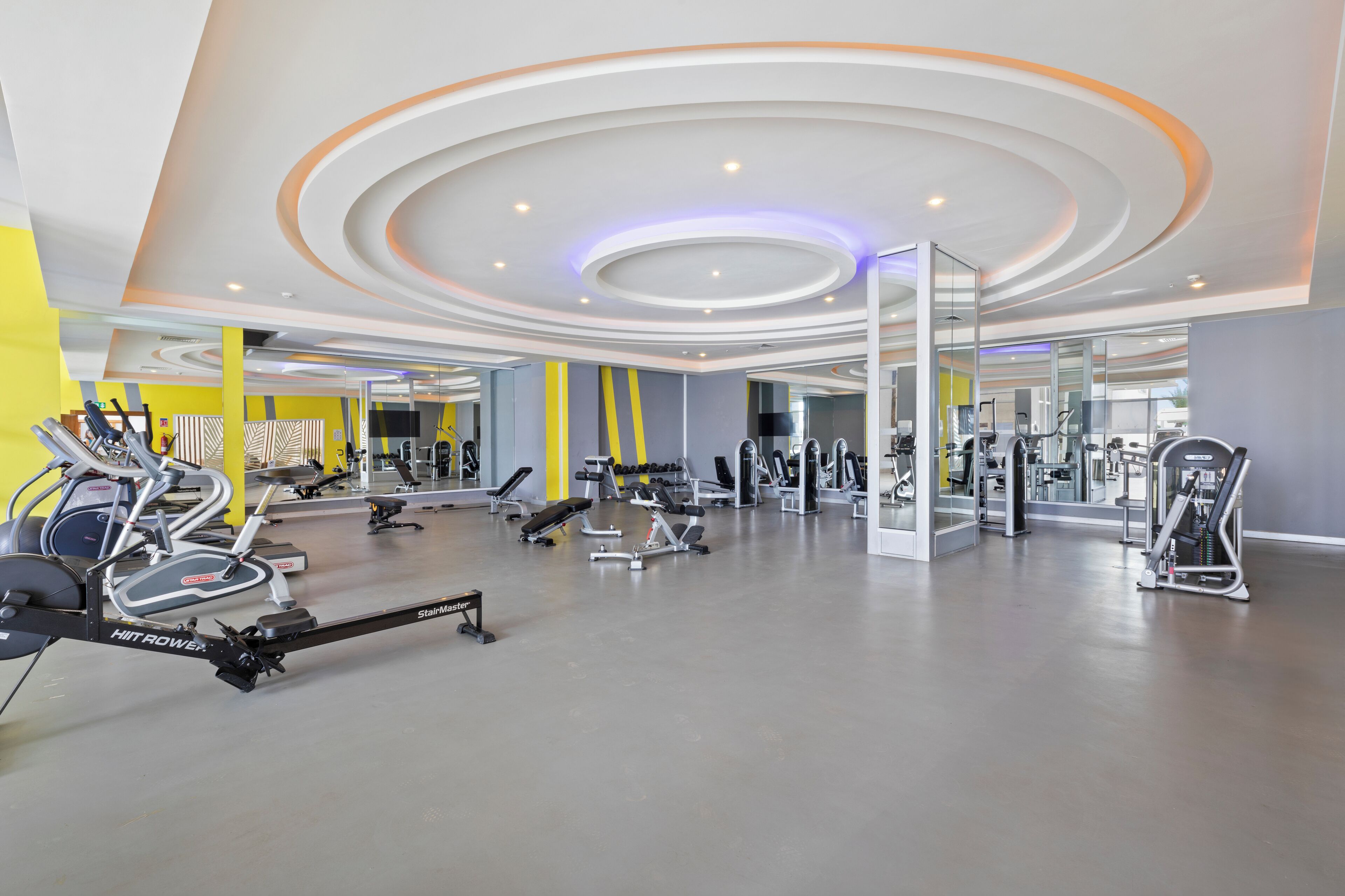 Ein modernes Fitnessstudio mit vielfältigen Trainingsgeräten, darunter Laufbänder und Kraftgeräte, und einem aufgeräumten, großzügigen Raum.