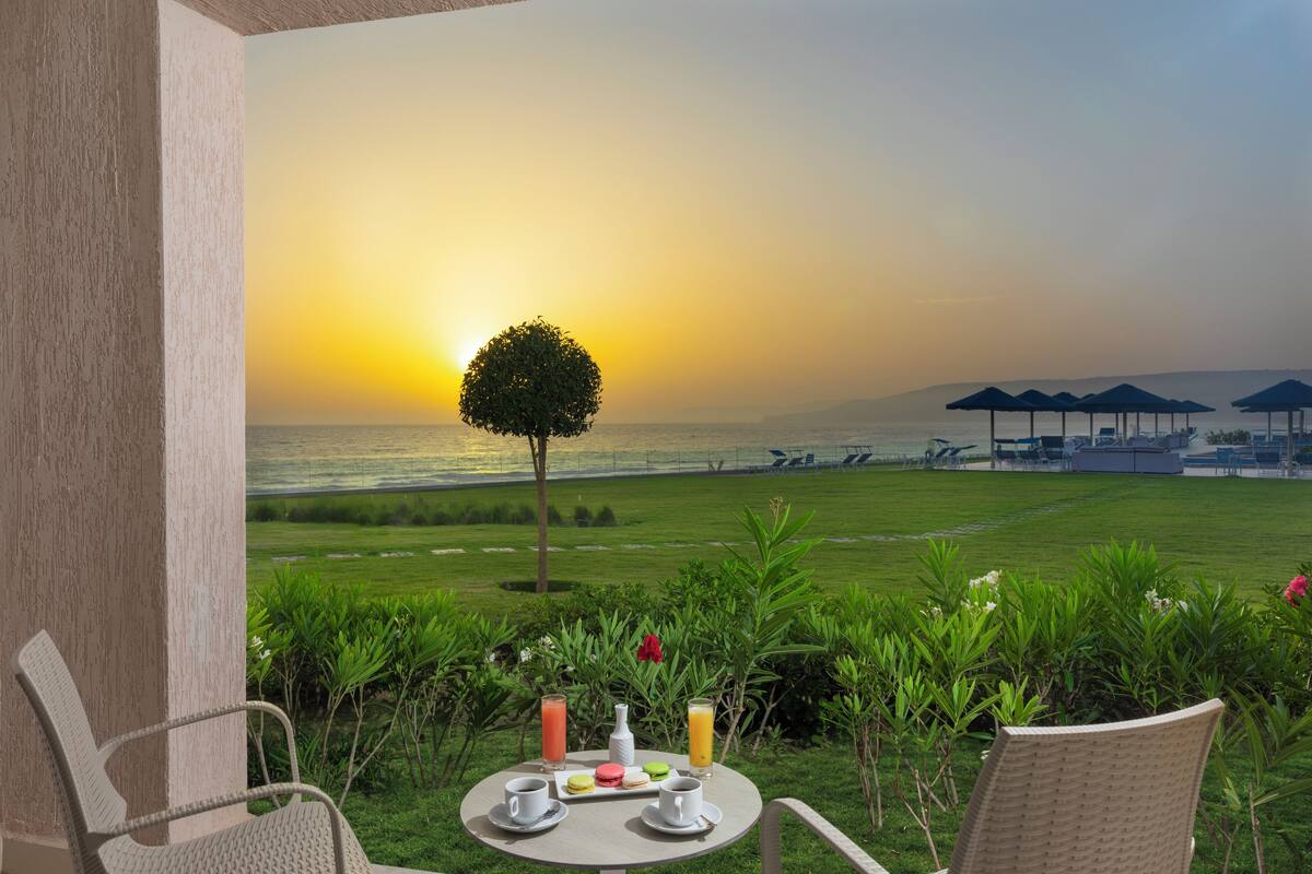 A table with breakfast items and a view of the sunset over the sea.