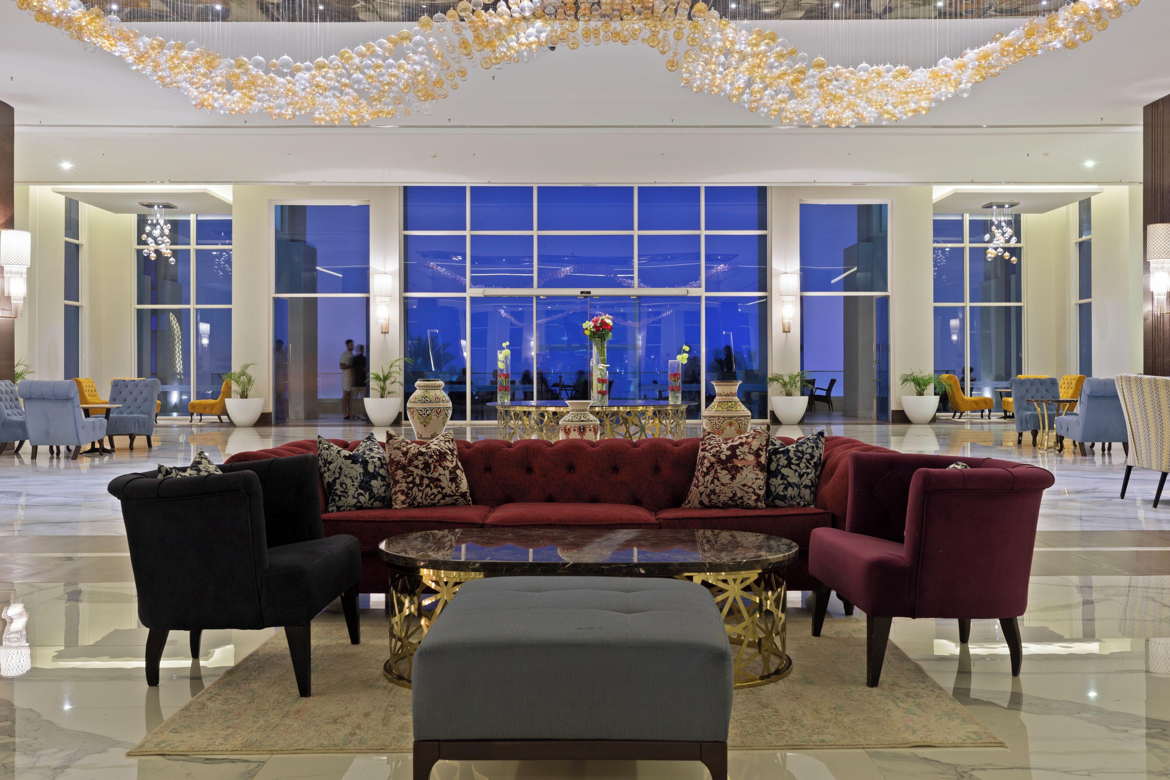 A spacious lobby with a red sofa, black and red armchairs, and a central coffee table.