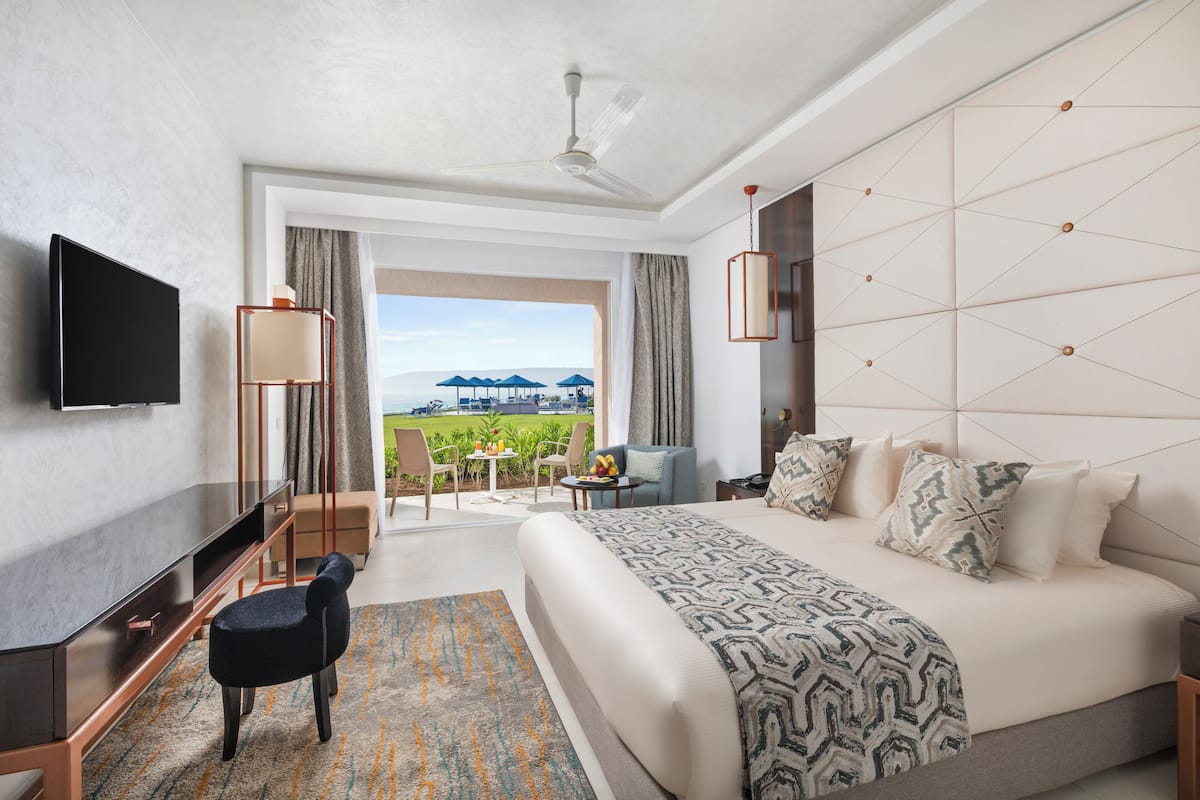 A hotel room with a large bed, a flat-screen TV, a desk, and a view of the outdoors.