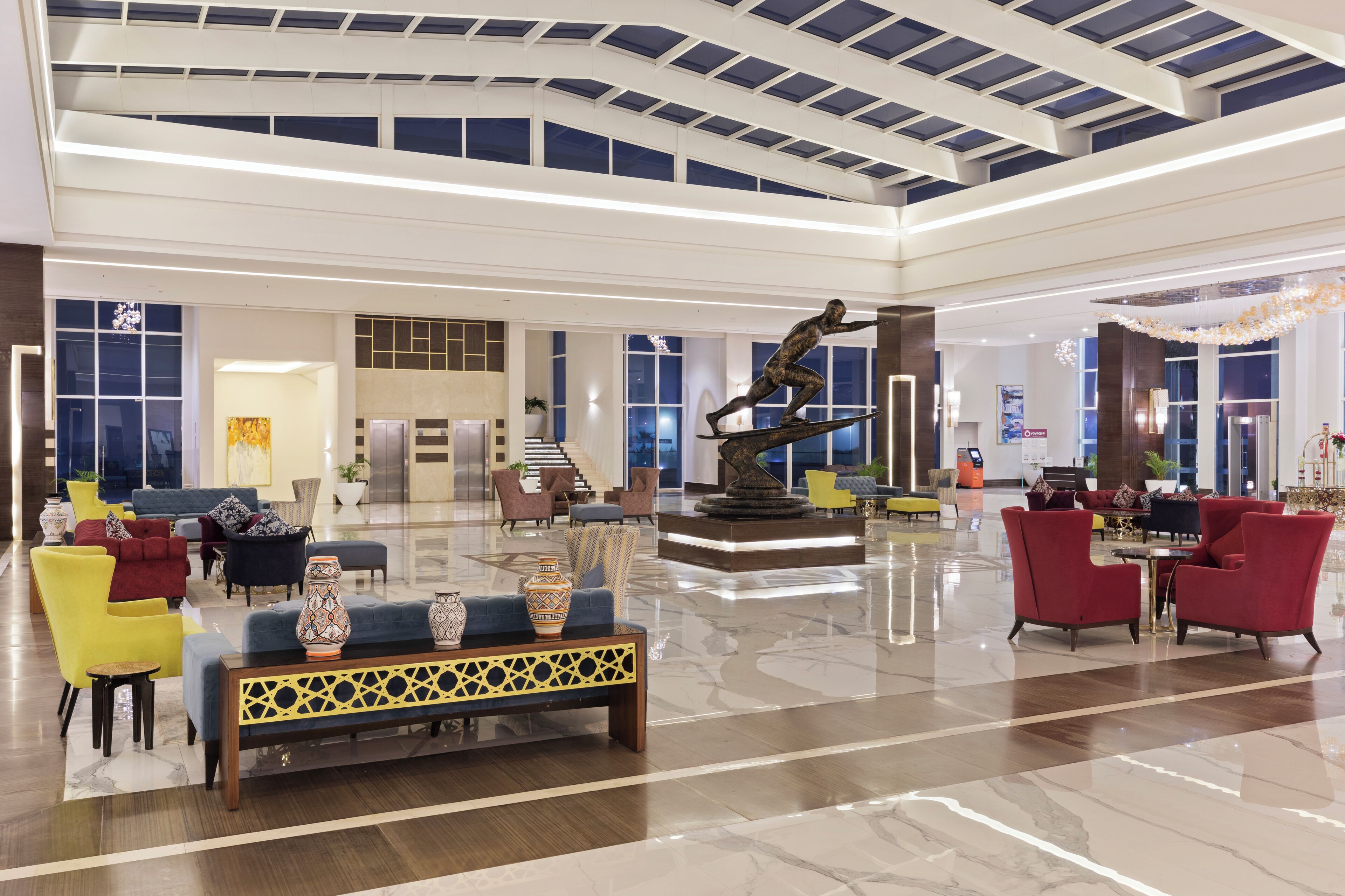 A spacious lobby with a high ceiling, a central fountain, and modern seating arrangements.