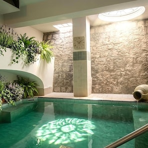 An indoor swimming pool with a stone wall and a clock. - Hotel Park Victoria (Forio)