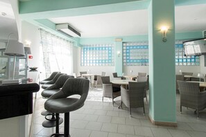 Un restaurante con barra, mesas y sillas para comer.