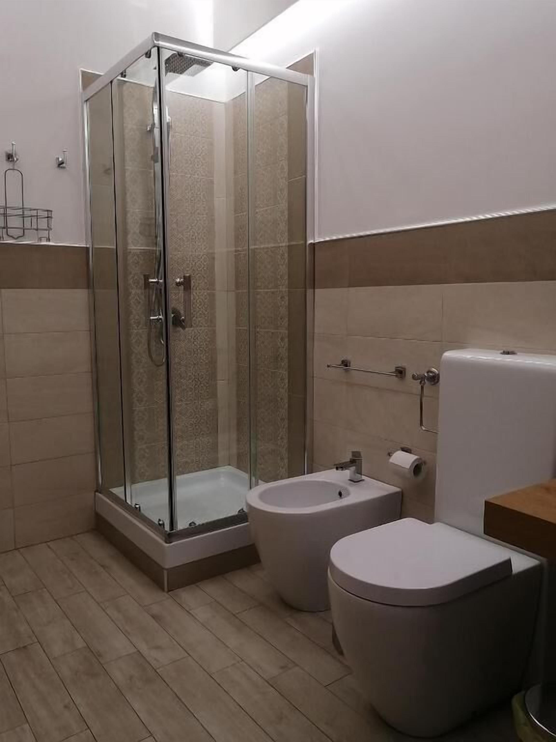 A bathroom with a glass-enclosed shower, a toilet, and a bidet.