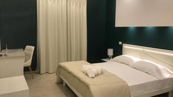 Una habitación de hotel con cama, escritorio, silla y cortina.