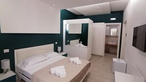 Een moderne hotelkamer met een groot bed, nachtkastje, spiegel en televisie.