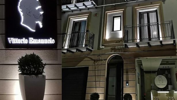 Een gebouw met een B&B bord, meerdere balkons en een goed verlichte ingang.