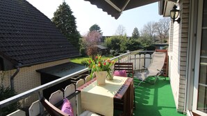 Une terrasse extérieure couverte, avec une table, des chaises et un pot de fleurs.