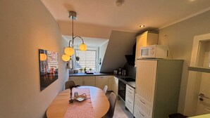 Une cuisine de taille réduite comprenant une table à manger, des chaises, un four à micro-ondes et des placards.