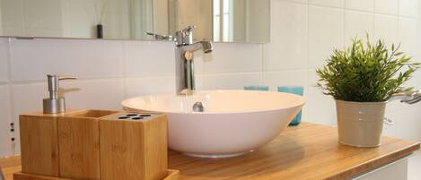 A bathroom with a wooden vanity, a white sink, and a mirror.