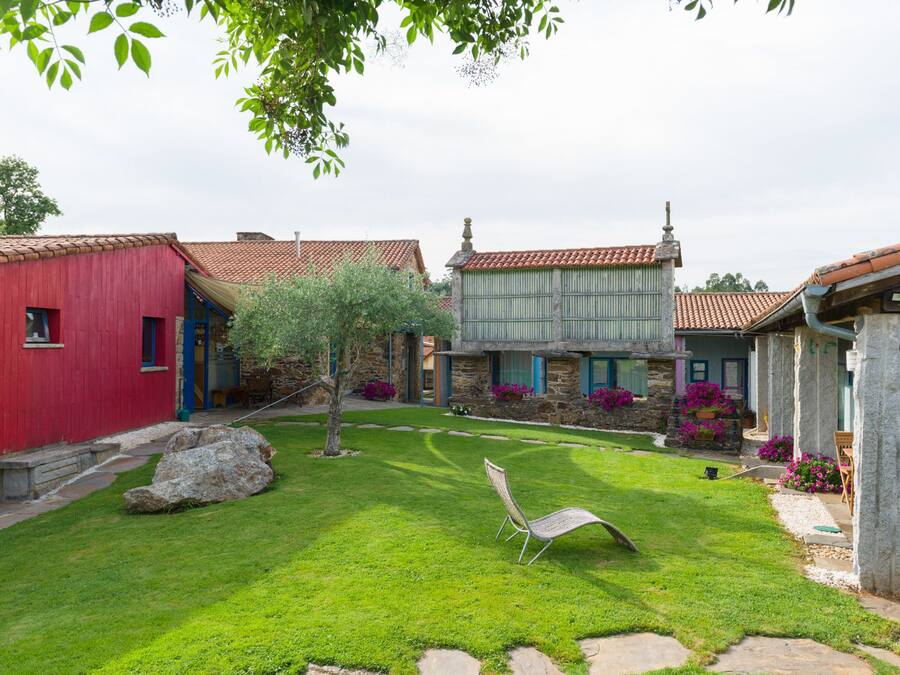 A courtyard with stone buildings, a lawn, and a chair.
