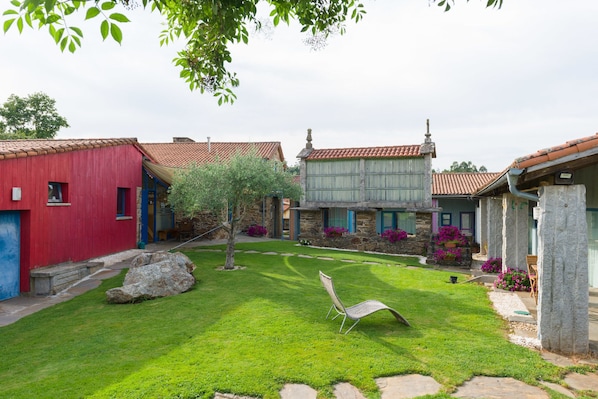 A courtyard with stone buildings, a lawn, and a chair.