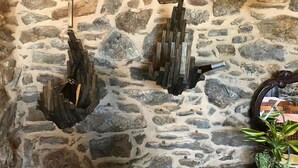 A stone wall with three wooden sculptures hanging from it. - Casa de Amancio (Santiago de Compostela)