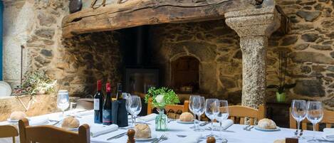 Un comedor rústico con paredes de piedra, muebles de madera y una chimenea de piedra.
