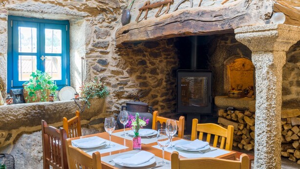 A stone-walled dining area with a wooden table set for four, surrounded by chairs. - Casa de Amancio (Santiago de Compostela)