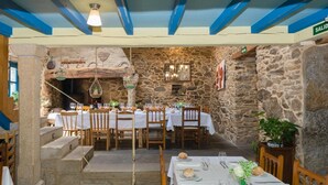 A restaurant with stone walls, wooden tables, and chairs. There are steps leading to a seating area. - Casa de Amancio (Santiago de Compostela)