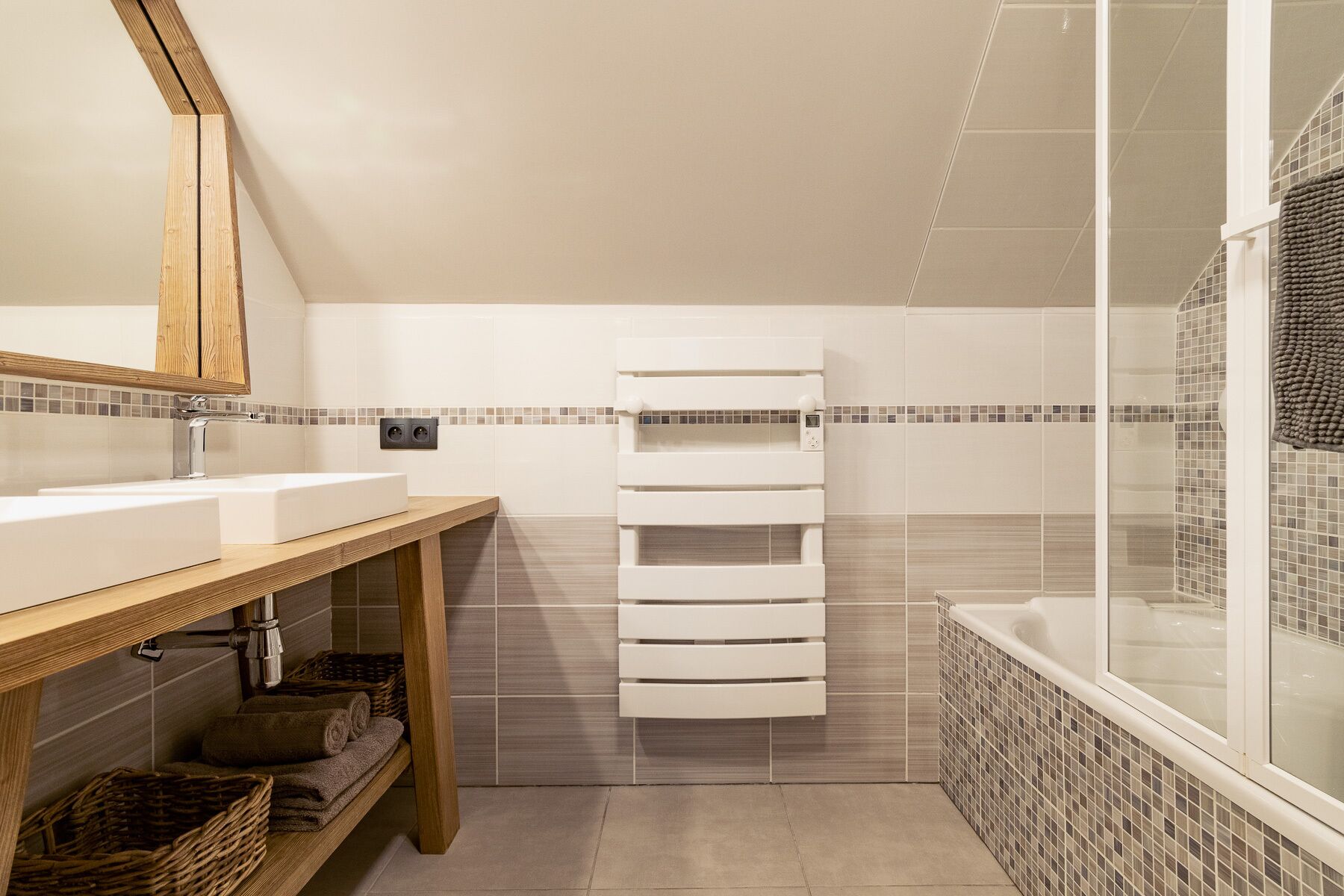 Une salle de bain moderne avec un meuble-lavabo en bois, un porte-serviettes blanc et une douche à l’italienne.