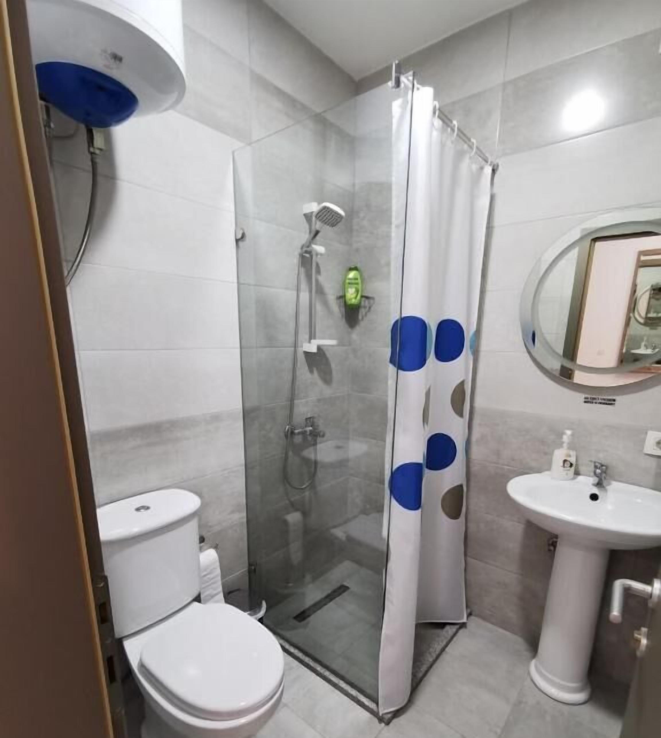 A bathroom with a glass-enclosed shower, a toilet, and a sink.