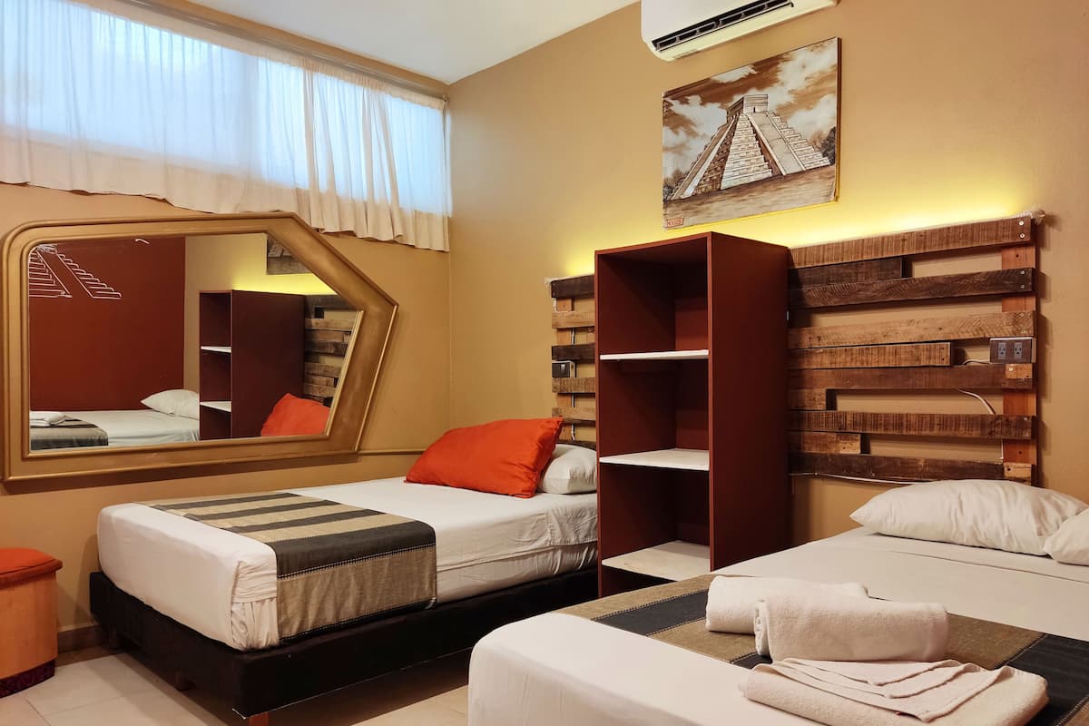 Habitación de hotel con dos camas, un espejo grande, un cabecero de madera y un cuadro de una pirámide.