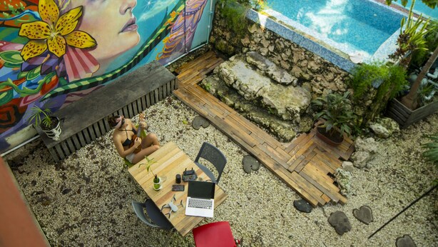 A pool area with a mural, a wooden deck, and a table with chairs. - Kaban 44 Hotel (Playa del Carmen)