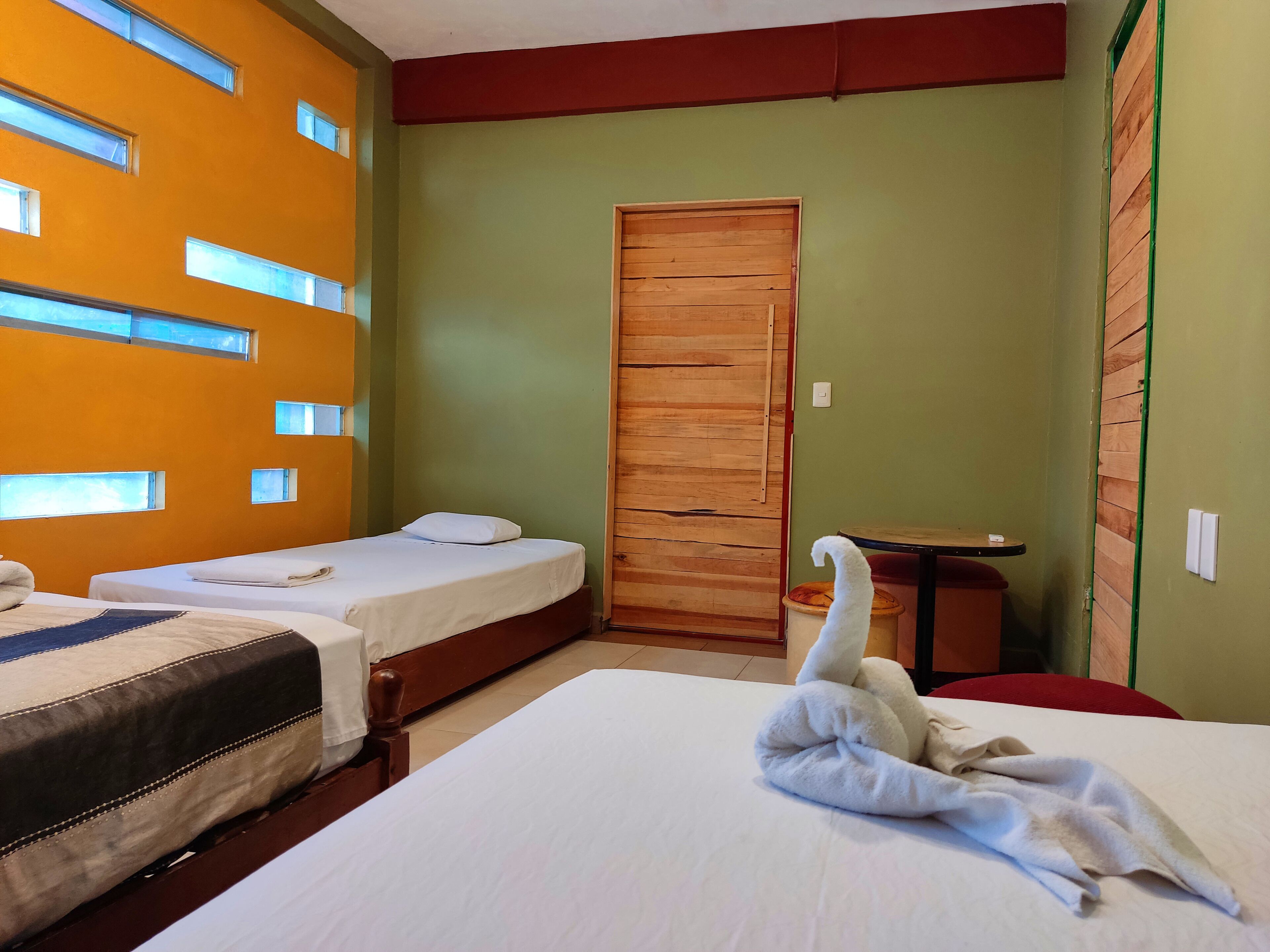 Una habitación de hotel con dos camas, una puerta de madera y una mesita.