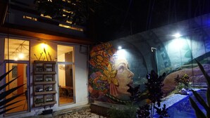 A building with a large mural on the exterior wall, a staircase leading to an upper level, and a small outdoor water feature. - Kaban 44 Hotel (Playa del Carmen)