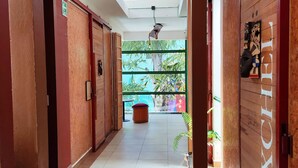 A hotel corridor with wooden doors, a tiled floor, and a skylight. - Kaban 44 Hotel (Playa del Carmen)