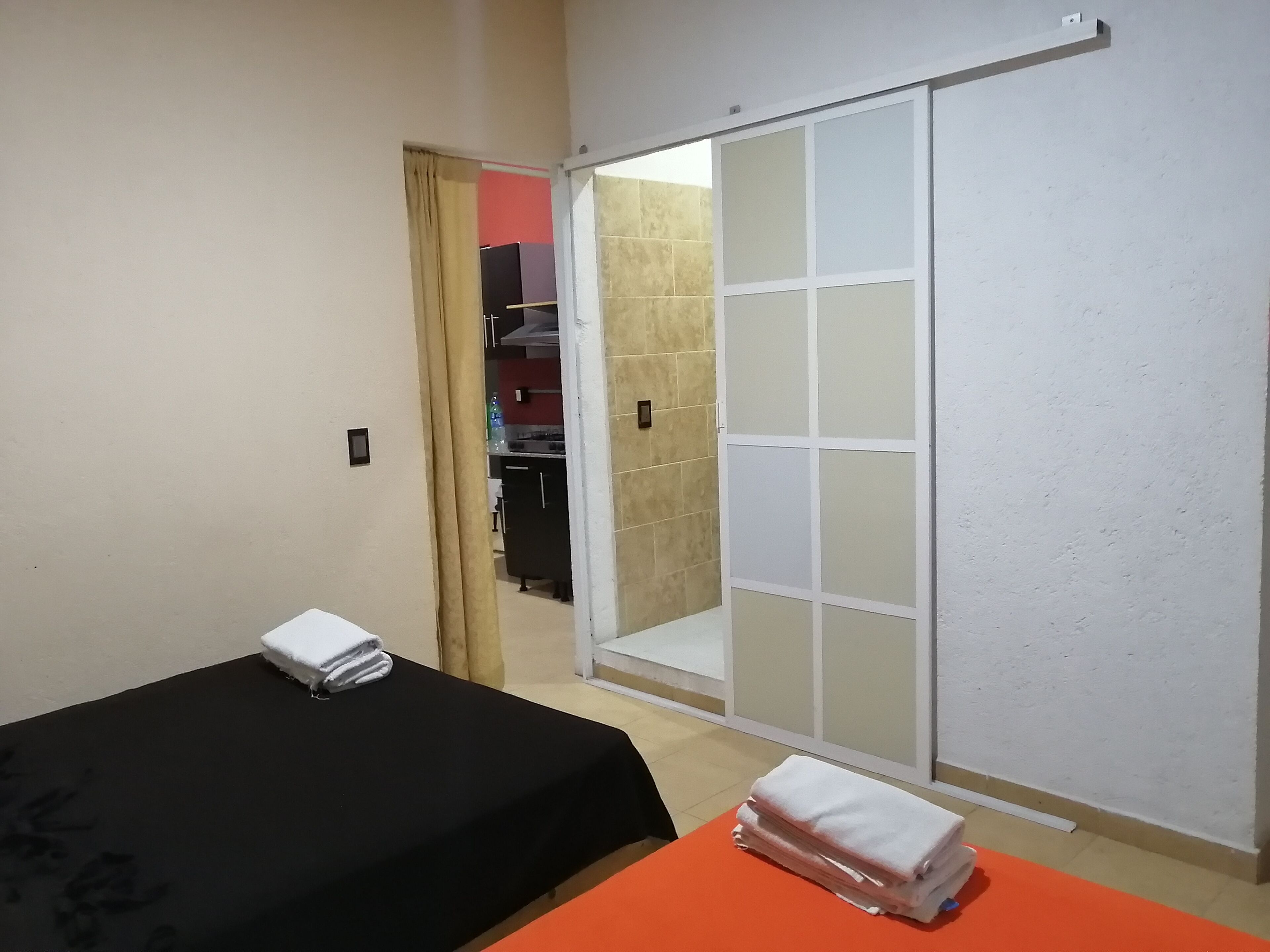 A hotel room with a bed, a table with towels, a sliding door, and a wardrobe.