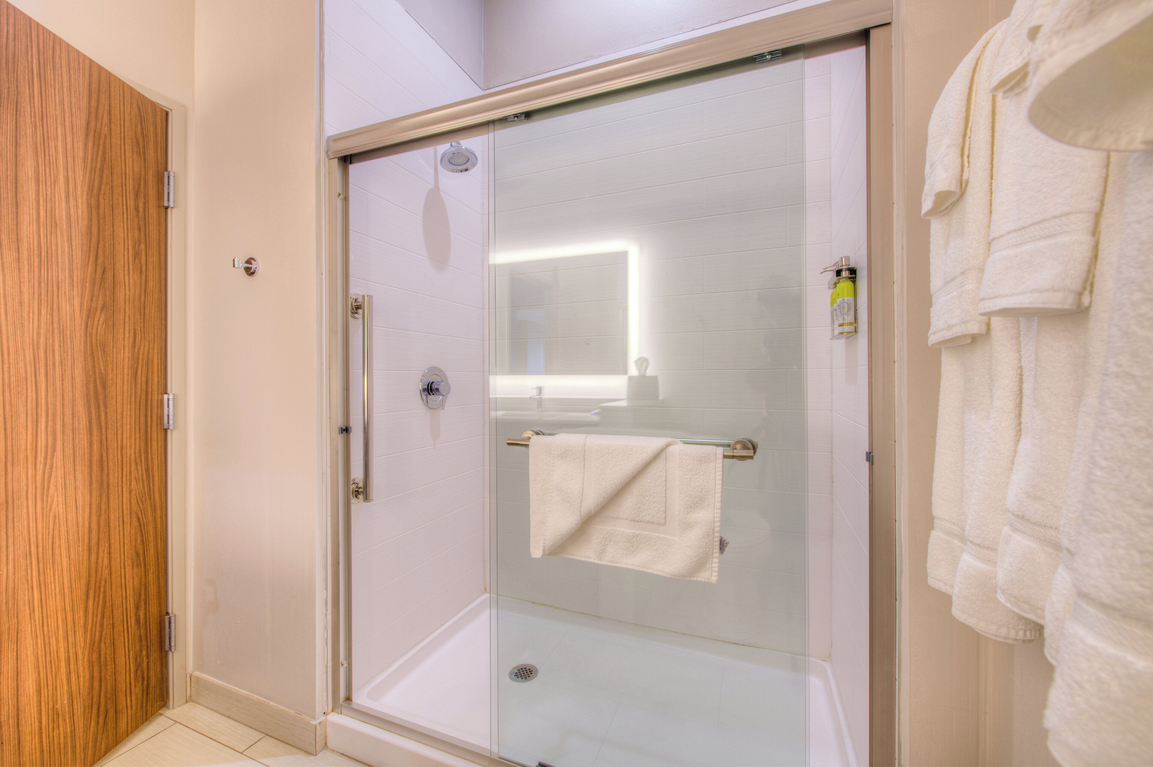 A glass-enclosed shower with a towel rack and a handheld showerhead.