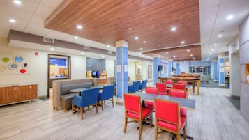 A spacious cafeteria with high ceilings, multiple seating areas, and a variety of tables and chairs.