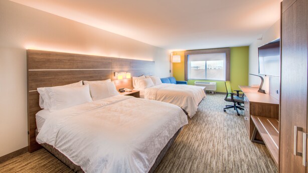 Quarto de hotel com duas camas, uma mesa, uma cadeira e janela com vista.