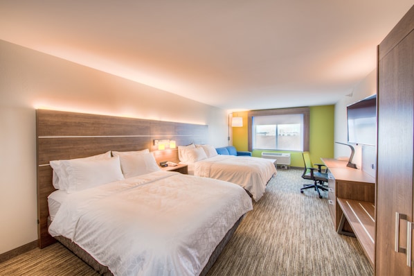 A hotel room with two beds, a desk, a chair, and a window with a view.