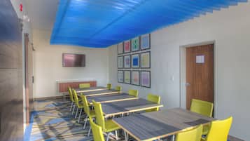 A conference room with tables and chairs, a flat-screen TV, and framed artwork on the wall.