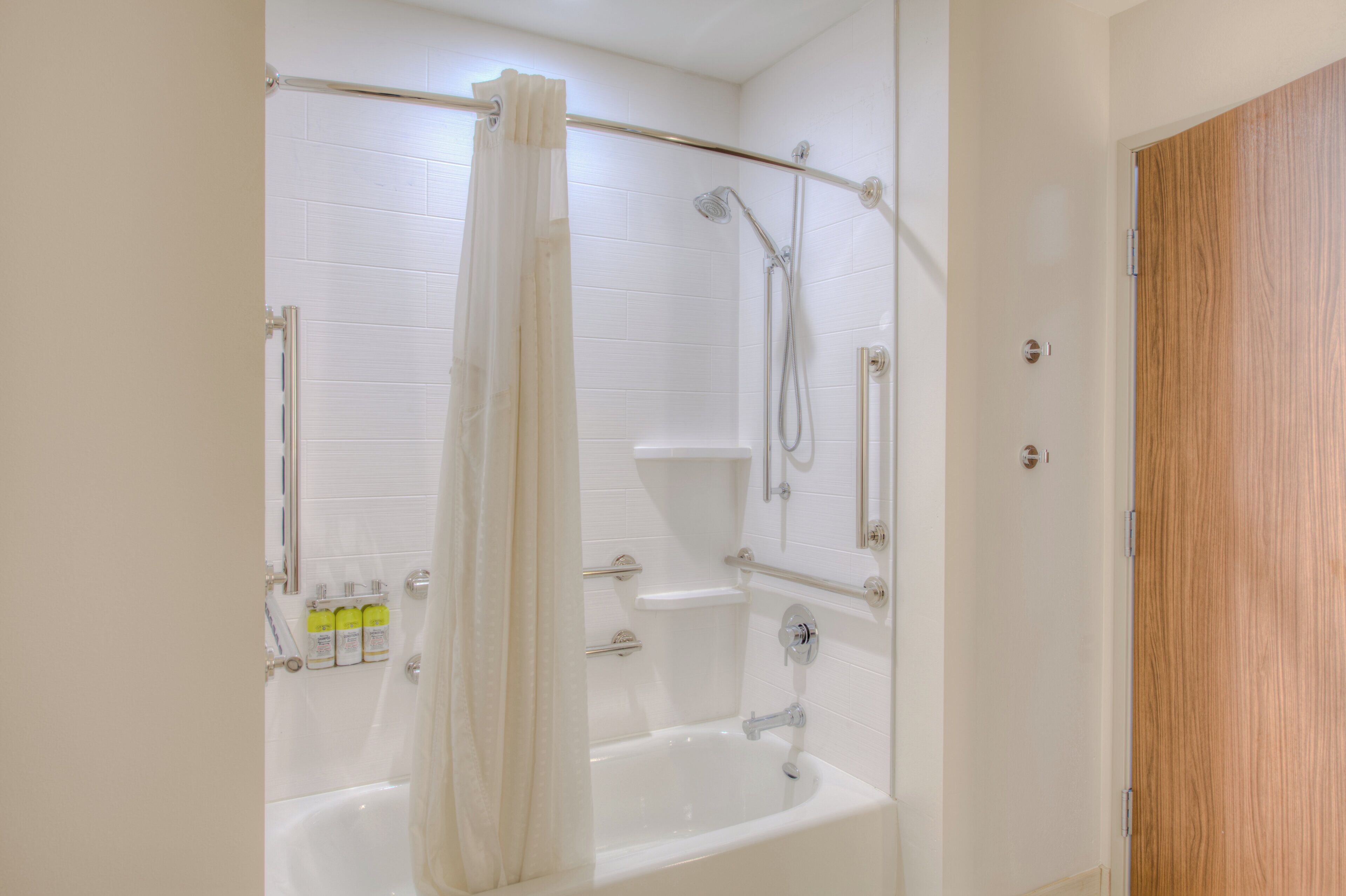 A bathroom with a bathtub, shower, and a wooden door.