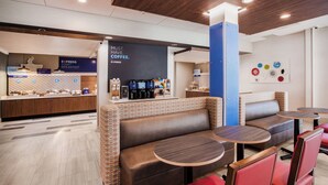 A modern coffee shop with seating areas, a coffee station, and a breakfast counter. - Holiday Inn Express & Suites Remington by IHG (Remington)