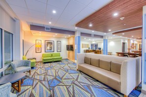A modern hotel lobby with a patterned carpet, seating areas, and artwork on the walls. - Holiday Inn Express & Suites Remington by IHG (Remington)