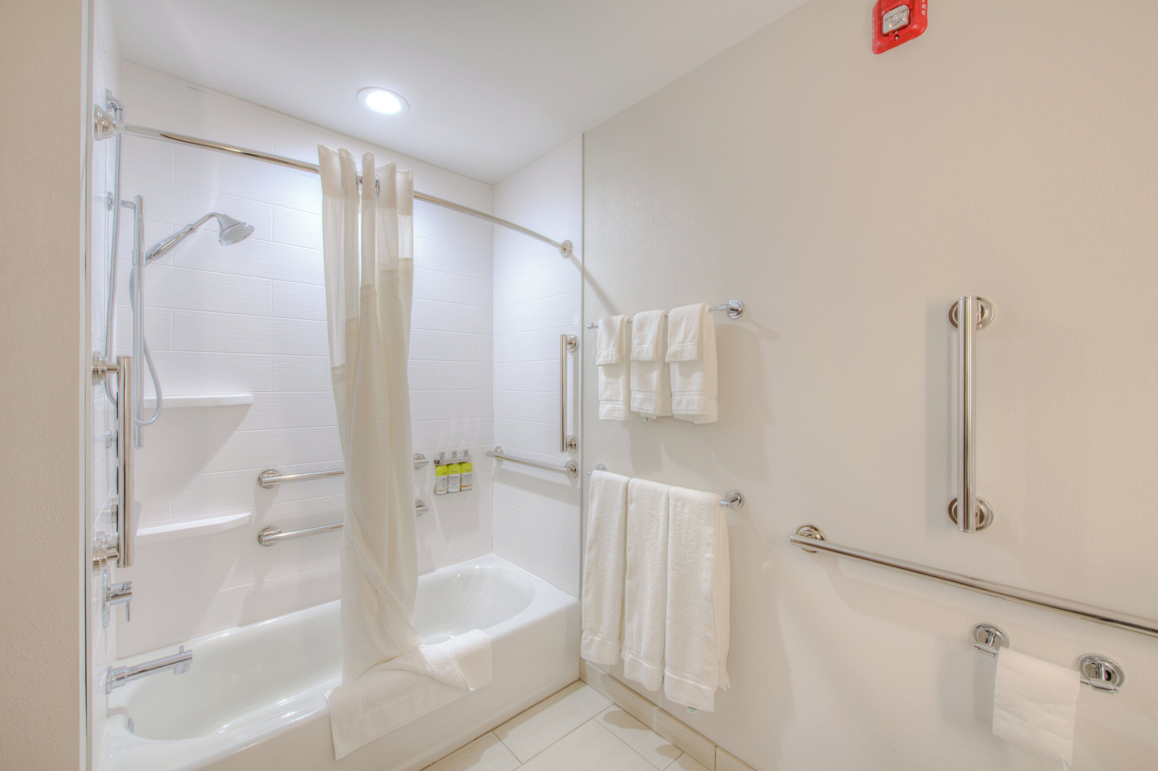 Un baño con bañera, ducha y barras de apoyo.