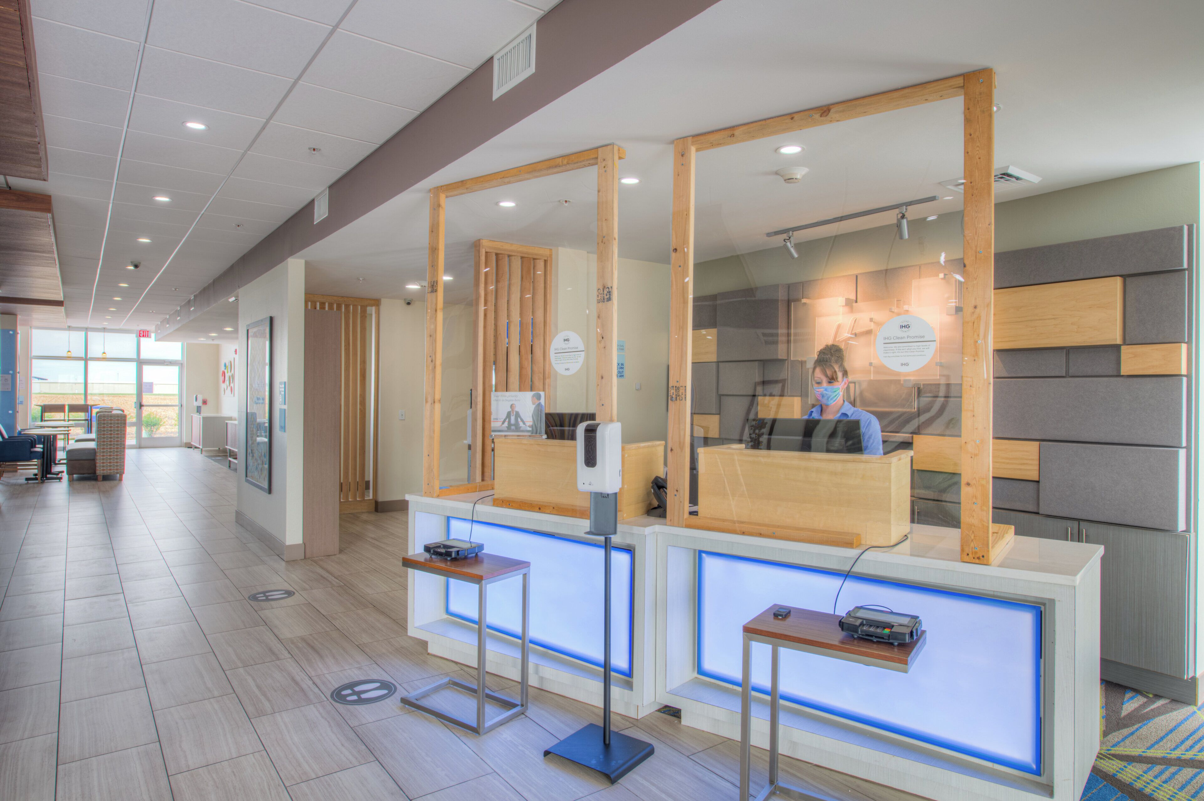 A reception area with a wooden reception desk, a digital screen, and a seating area with chairs.
