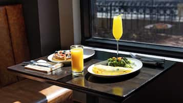 A table with breakfast items, a glass of orange juice, and a glass of orange juice with a straw.